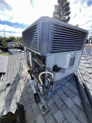Technician replacing blower motor on rooftop AC unit during repair in Rancho Cordova
