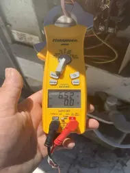 Technician testing electrical readings on an outdoor AC unit during diagnostic service in Sacramento