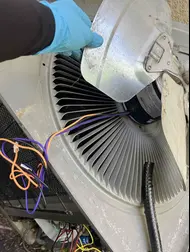 Servicing the components of the outdoor AC unit where the AC fan required repair