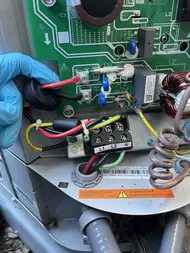 Technician testing wiring and power at a heat pump control board during AC troubleshooting in Sacramento